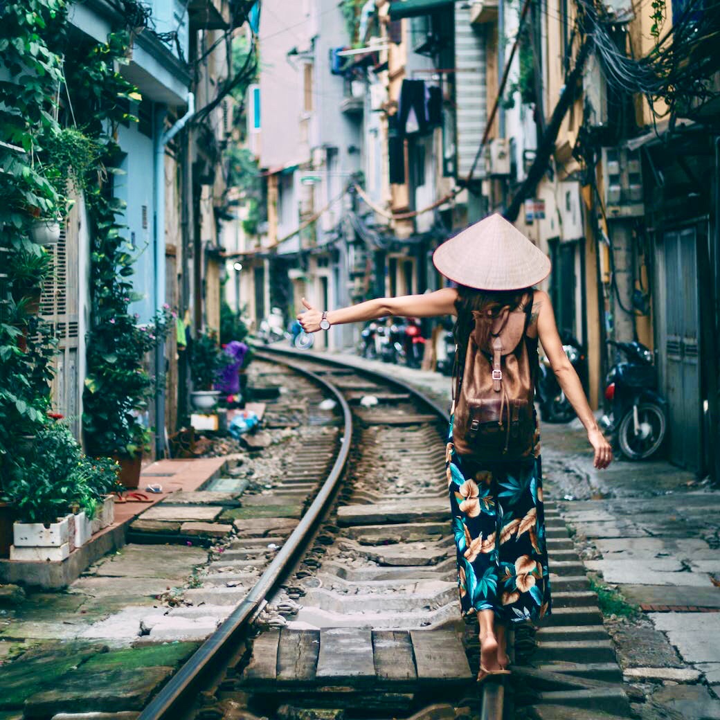 Vietnamese women in traditional conical hats walking along a rural path in Vietnam